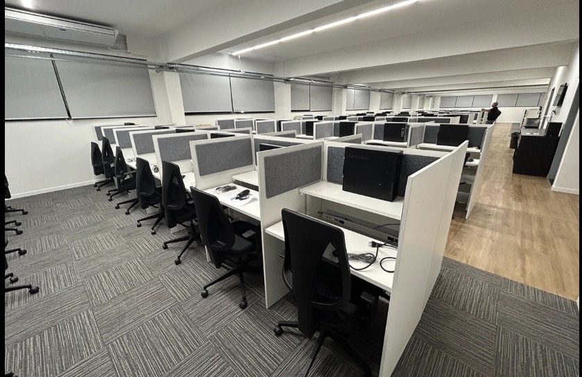 Salão de call center com fileiras de posições de atendimento e cadeiras ergonômicas